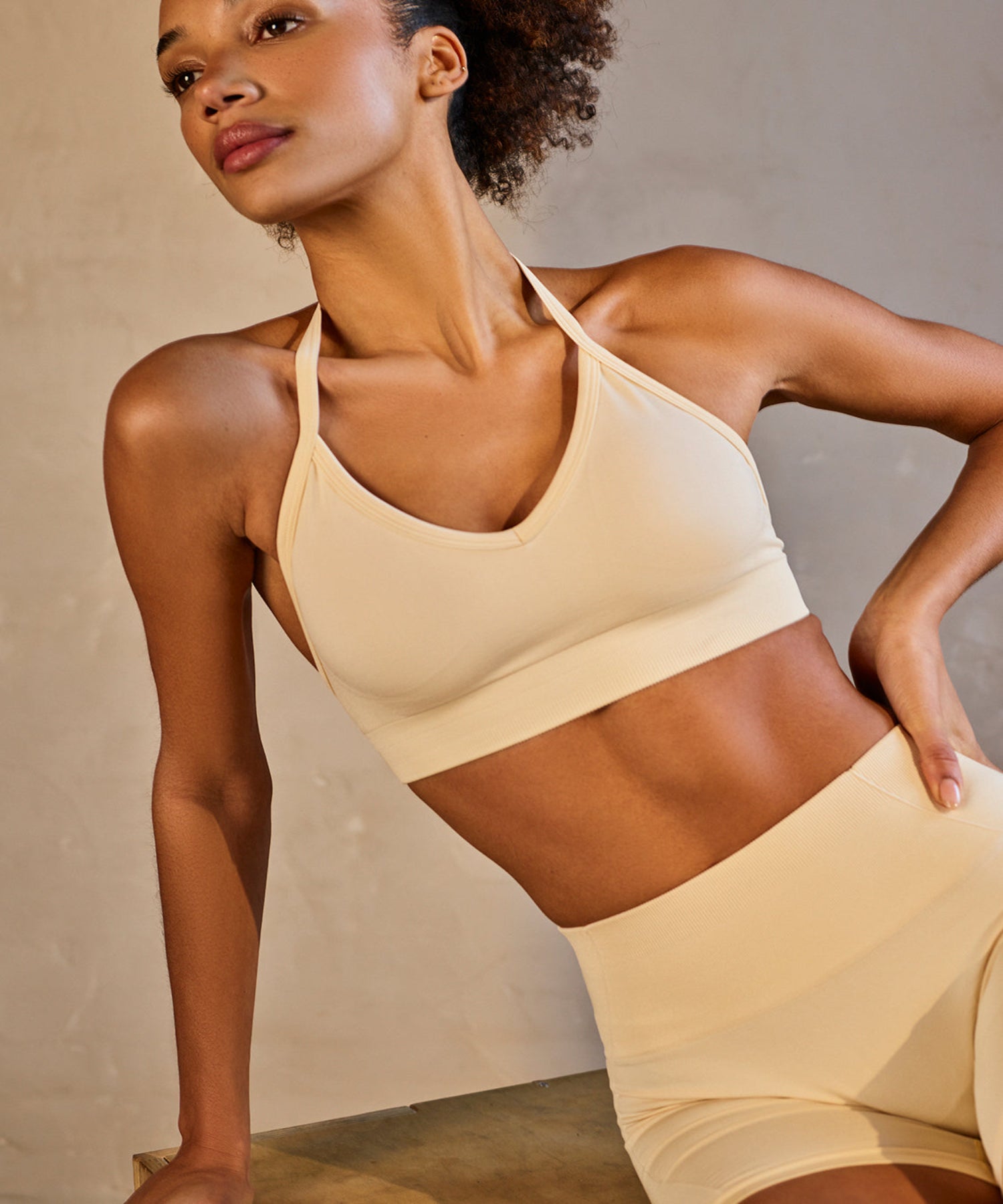 Woman wearing a beige sports bra and shorts set against a neutral background